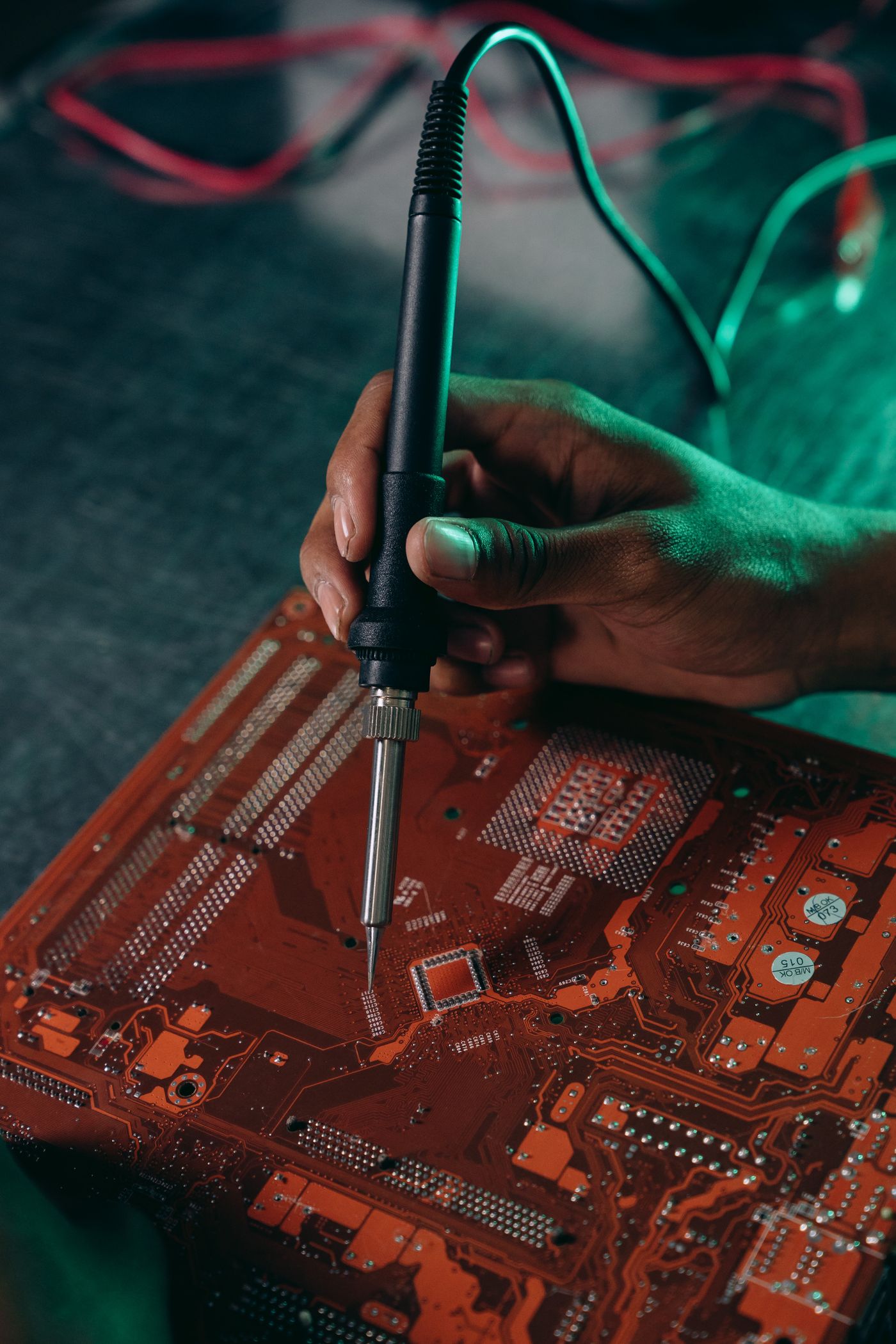 Close-up of a hand using a soldering iron on a circuit board